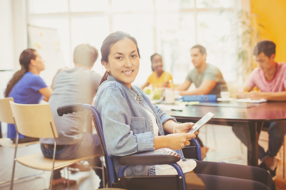 A smiling woman in a wheelchair joins in with others.